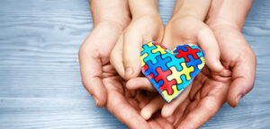 two pairs of hands holding a heart made of puzzle pieces